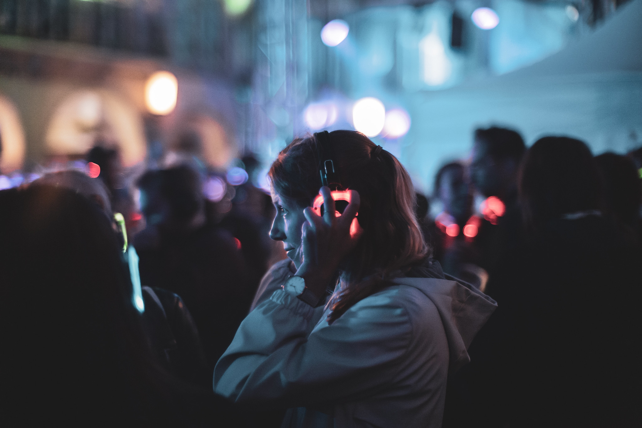 Persoon met draadloze koptelefoon danst op silent disco evenement met kleurrijke lichten op achtergrond