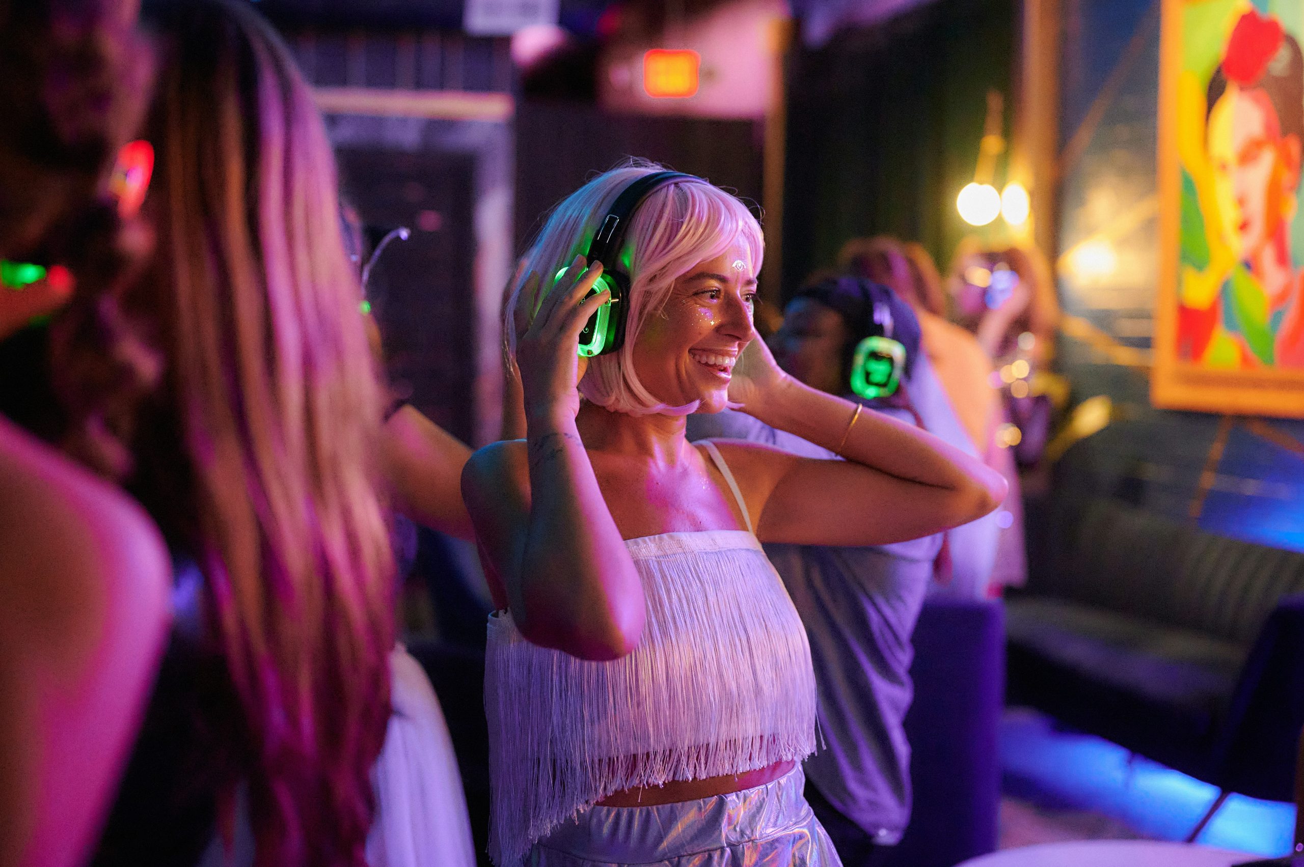 Vrouw danst vrolijk met draadloze koptelefoon tijdens silent disco feest met kleurrijke verlichting